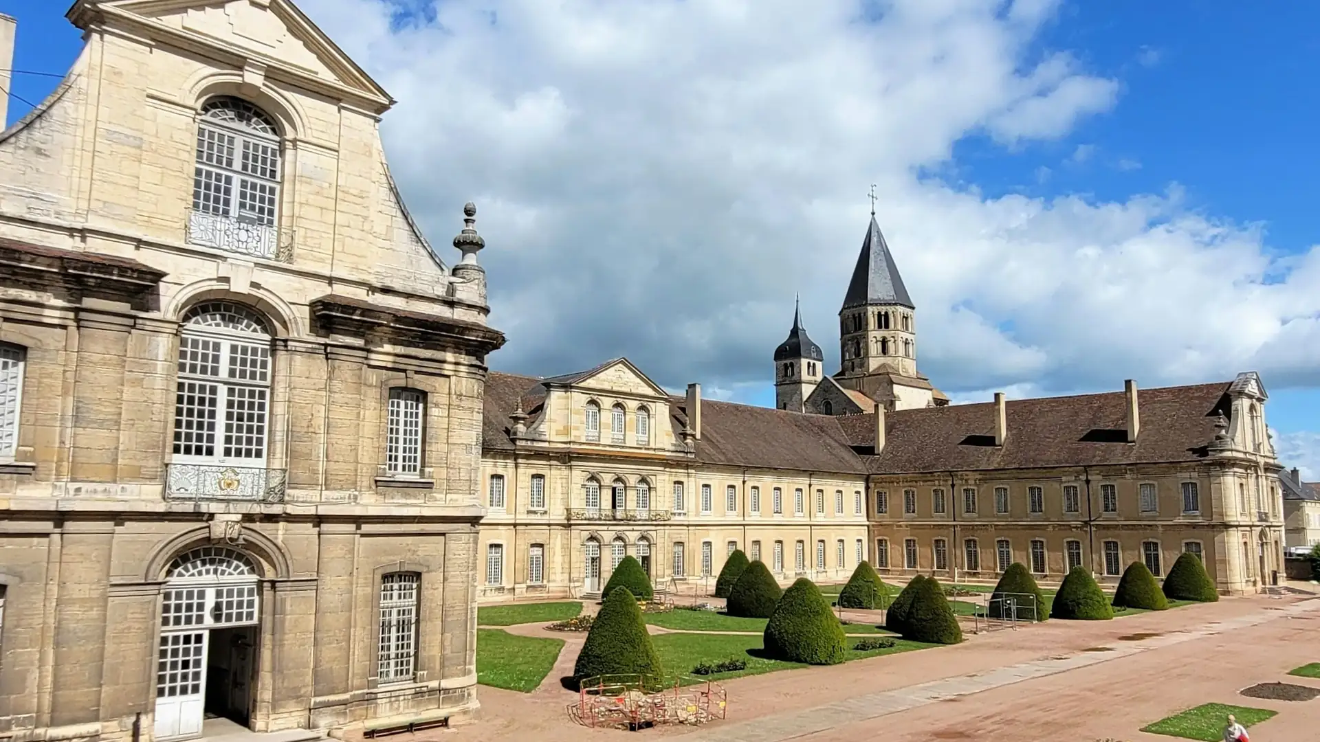 The abbatial palace courtyard at Cluny, clipped yews on the lawn and the octagonal Clocher de l'Eau Bénite rising above the long roofs