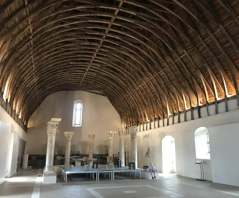 The timber-vaulted roof of the Farinier at Cluny Abbey, above the carved Romanesque capitals rescued from the lost church