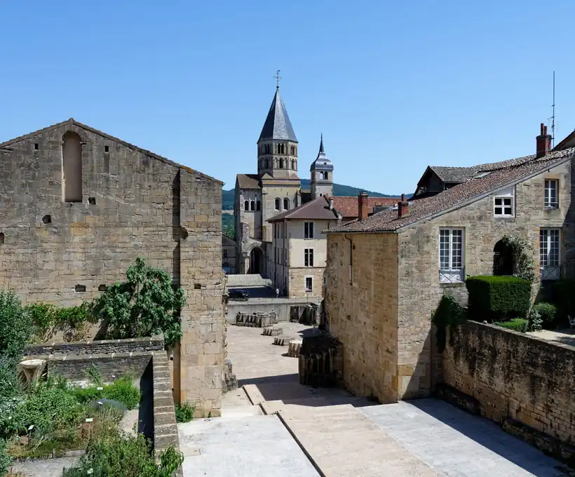 The ruined precinct walls of Cluny Abbey, with the bell tower rising behind the cleared footprint of the lost nave